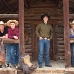 wranglers smiling at log cabin at Three Bars Ranch