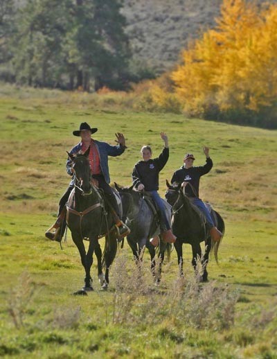 man and kids on horses waving