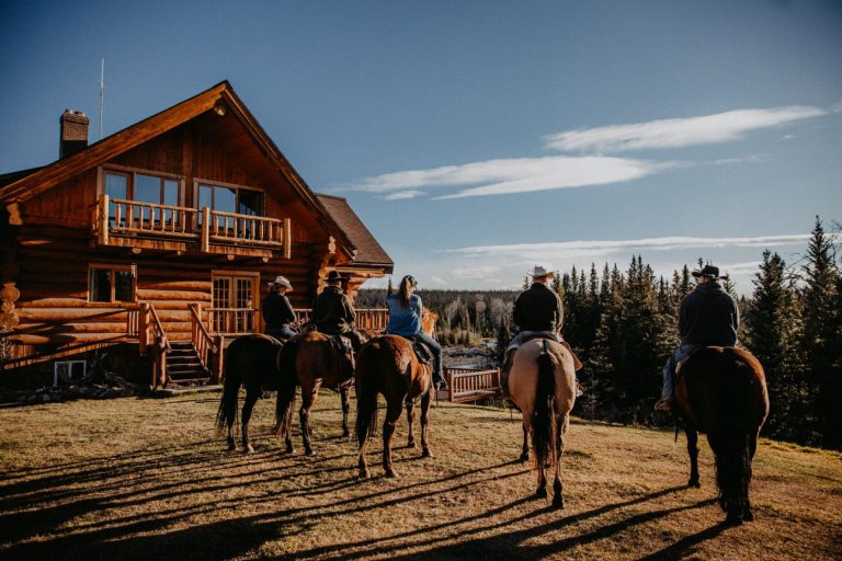 wood lodge with five ranchers and their horses