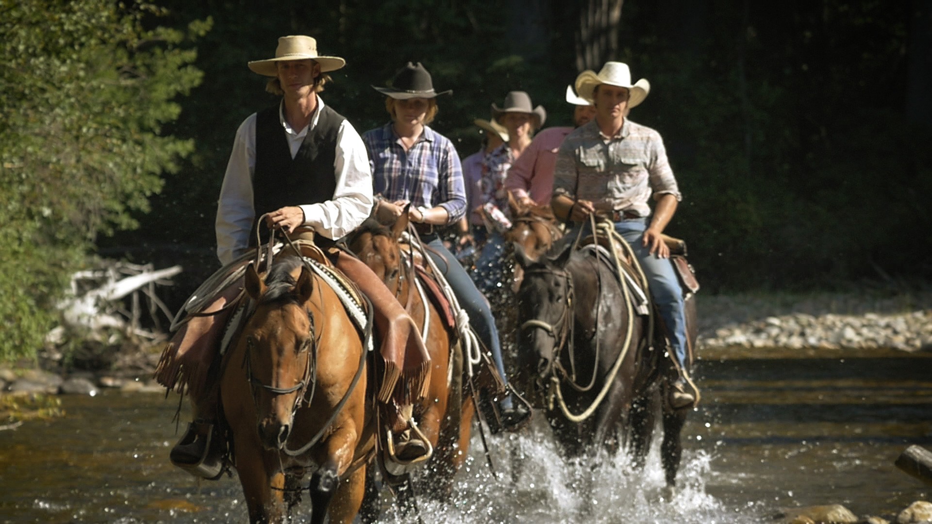 wranglers crossing the river at the ranch